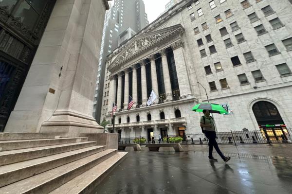 A man walking past the New York Stock Exchange building on Wall Street