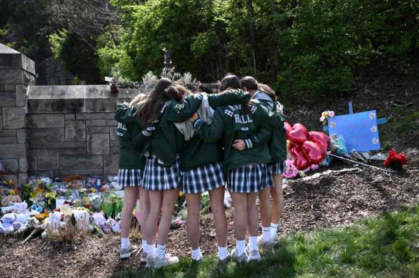 Girls embrace in front of a makeshift memorial for victims by the Covenant School building at the Covenant Presbyterian Church following a shooting, in Nashville, Tennessee, March 28, 2023. 