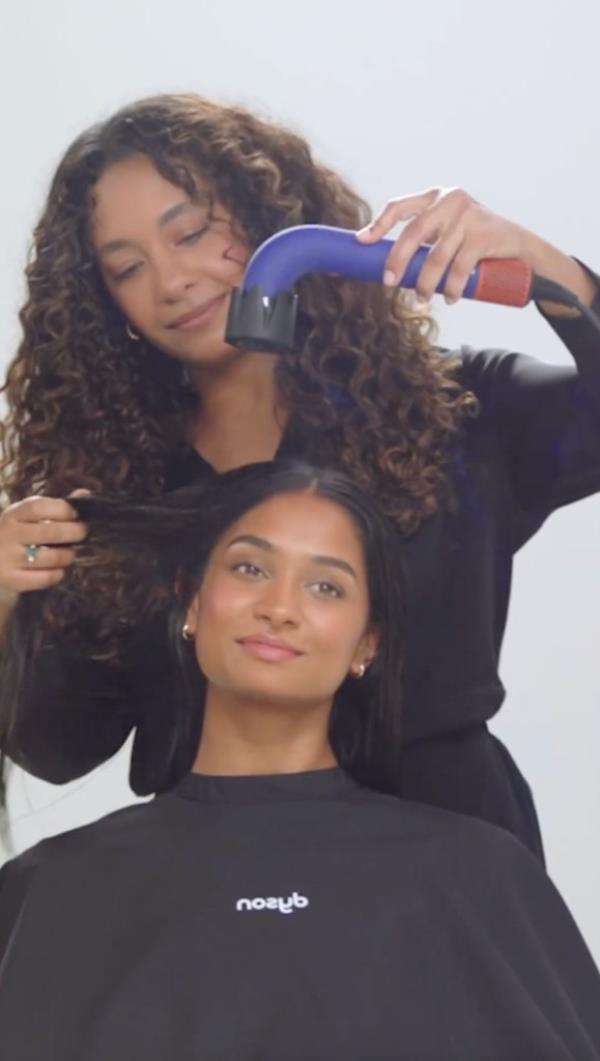 Woman using hairdryer on another woman