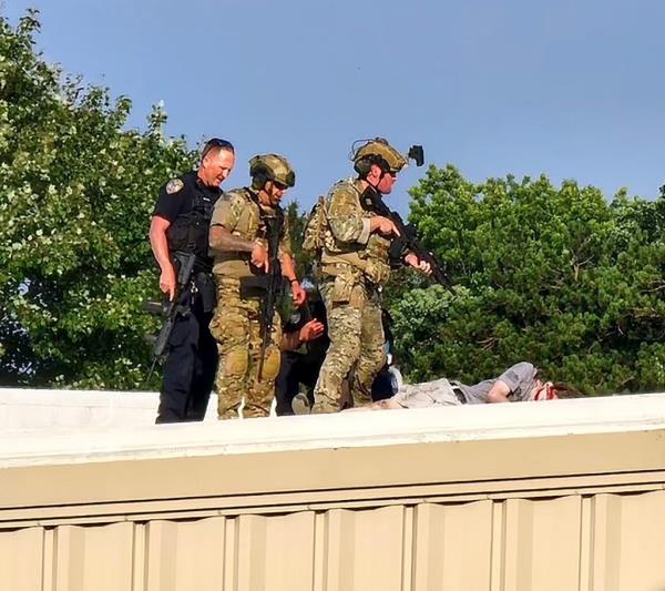 Officers stand over the body of the would-be assassin. 