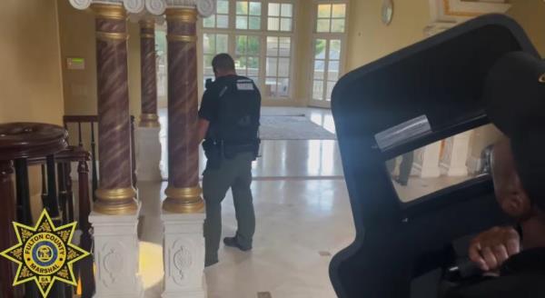 Video shows the marshals with police shields and long guns scouring the luxurious mansion featuring multiple interior Greek columns