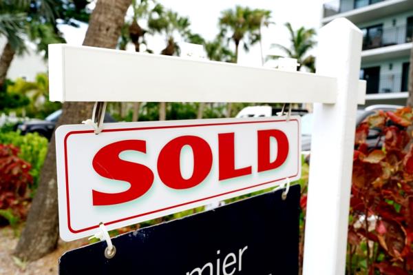 A sold sign displayed in front of a co<em></em>ndominium building in Indian Shores, Florida, signifying a completed real estate transaction.