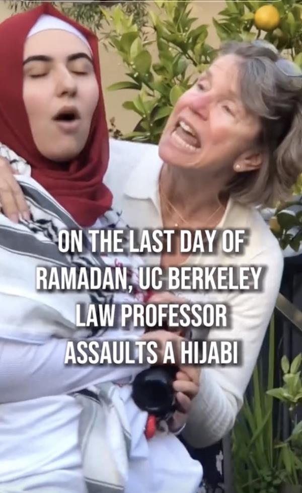 A woman in a hijab appears to shout and read from a phone in a crowd of people, one of them masked, another a woman wearing a hijab