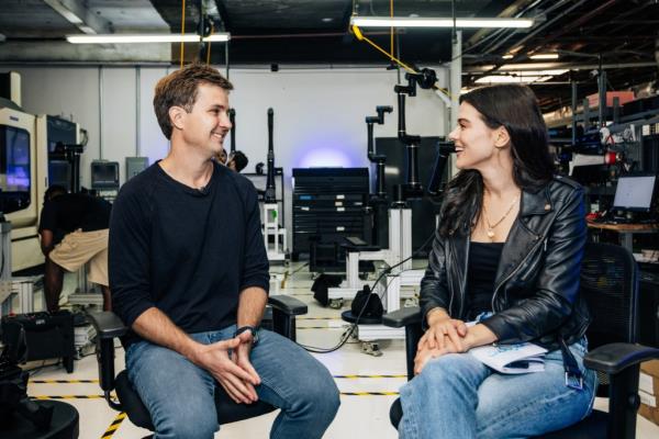 Founder and CEO of Standard Bots, Evan Beard and Lydia Moynihan, sitting in chairs at their office in Glen Cove, Long Island.