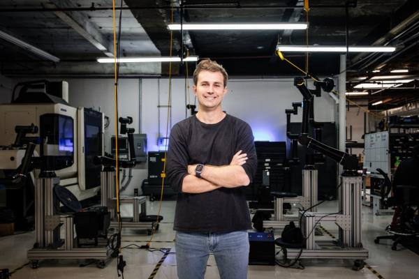 Founder and CEO of Standard Bots, Evan Beard, standing in a room filled with equipment at Standard Bots in Glen Cove, Long Island.