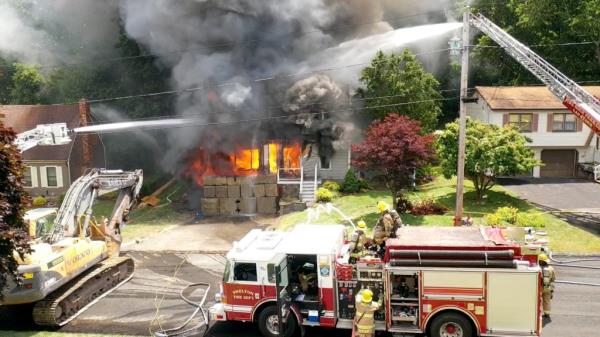 Firefighters respo<em></em>nding to a structure fire during a thunderstorm, with fireworks erupting from the garage of a 1.5 story cape home in Shelton, CT on June 22, 2024