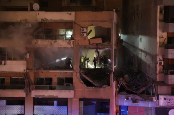 People stand at a damaged building following an explosion at the Beirut suburb of Dahiyeh, Lebanon January 2, 2024.