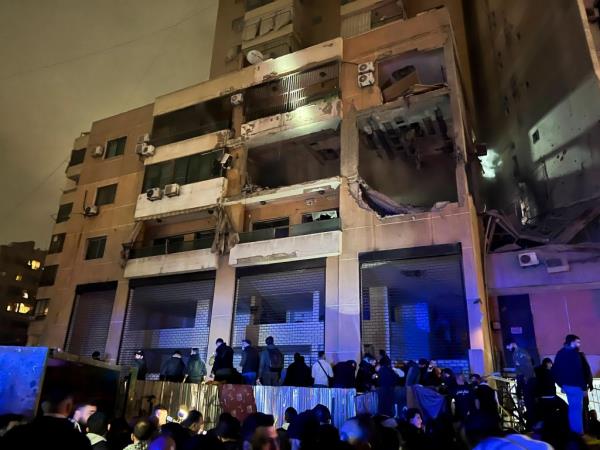 People stand outside a building after an explosion in southern Beirut, Lebanon, Tuesday, Jan. 2, 2024.