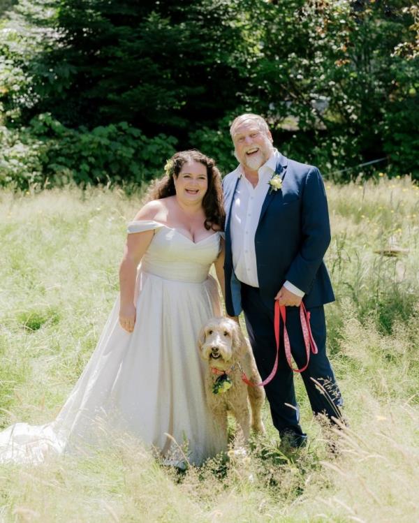 Actor Julien Arnold and his wife Sheiny Satanove posing happily on their wedding day in a field with a dog