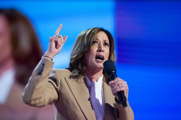 US Vice President Kamala Harris speaking at the 2024 Democratic Natio<em></em>nal Co<em></em>nvention in Chicago, holding a microphone and pointing upwards