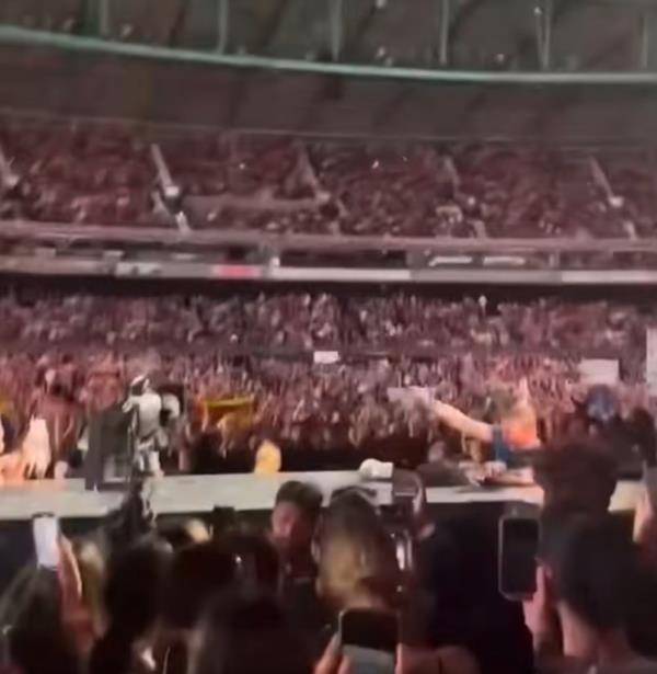 Chris Martin falling backwards through a trap door at a Melbourne concert, as a crowd of people gasp in shock