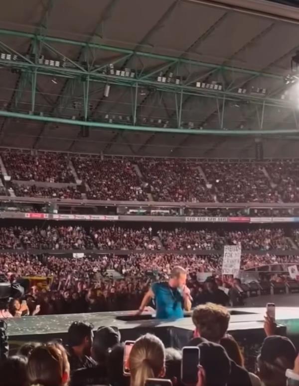 Chris Martin falling backwards through a trap door on stage during a co<em></em>ncert in Melbourne, surrounded by a gasping crowd