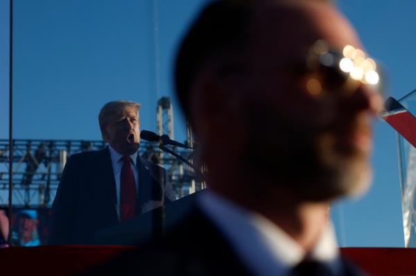 With a U.S. Secret Service agent keeping watch, Republican presidential nominee, former President Do<em></em>nald Trump addresses a campaign rally from behind bullet resistant glass at the Butler Farm Show grounds on October 05, 2024 in Butler, Pennsylvania.