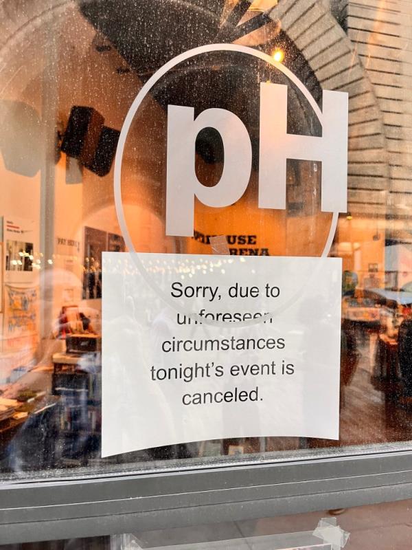 Sign on a glass door saying an event was cancelled.