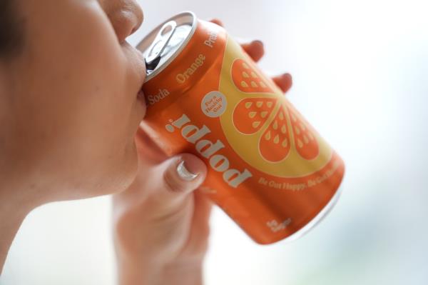 Person in New York drinking Poppi, a prebiotic soda, described as a guilt-free indulgence by a fitness instructor