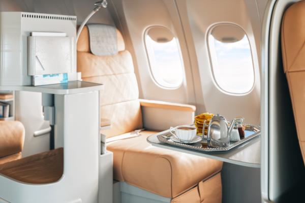 First class airplane seat with a tray of dessert and coffee served on board