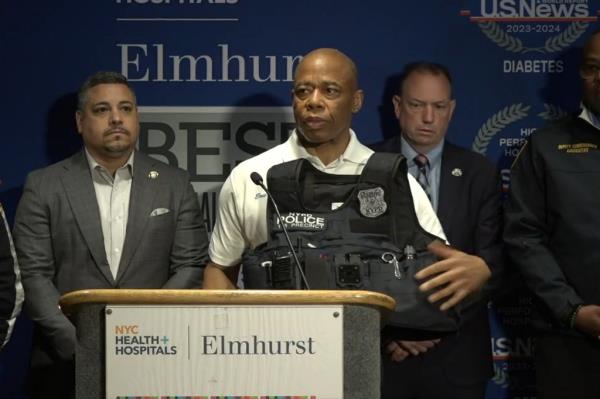 Mayor Eric Adams standing at a podium, displaying a police vest with a bullet hole related to Venezuelan migrant Bernardo Raul Castro Mata's arrest in Queens.