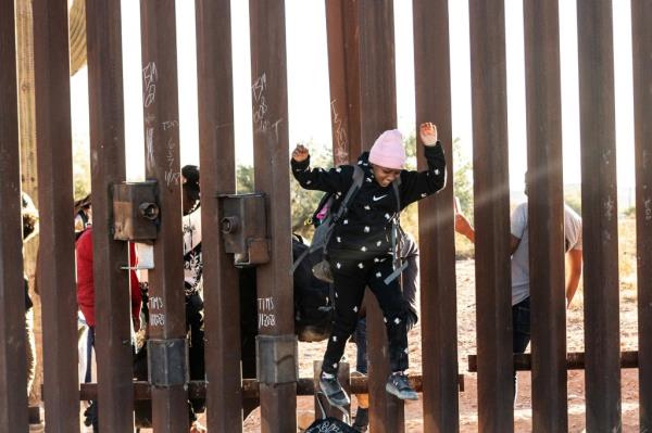 A migrant child jumps to cross the border wall through a gap into the U.S. from Mexico, as the number of migrants surges in the border town of Lukeville, Arizona, U.S. December 12, 2023.