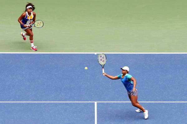 Naomi Osaka and Mari Osaka playing doubles tennis as a team. 