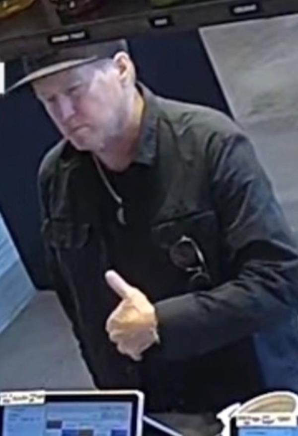 Close-up of the man at the counter wearing a ba<em></em>seball cap.