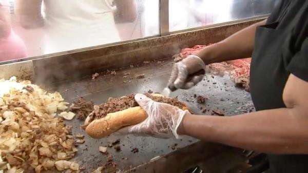 Man prepares cheesesteak sandwich