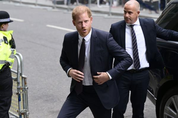 Prince Harry, Duke of Sussex and Peter Bosz among a group of men in suits walking on the street, reflecting royal family dynamics.