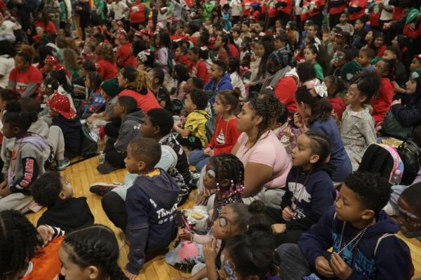 A group of kids sitting on the gymnasium floor at the Police Athletic League's annual holiday party at their Harlem headquarters