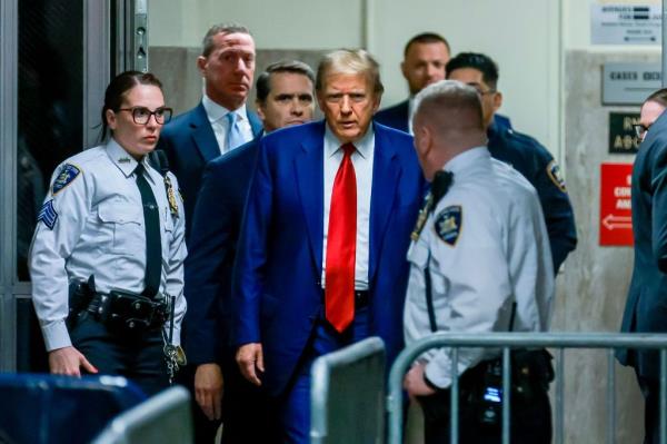 Former U.S. President Do<em></em>nald Trump in suit and tie accompanied by police officers, arriving at New York Criminal Court for a hearing, 25 March 2024