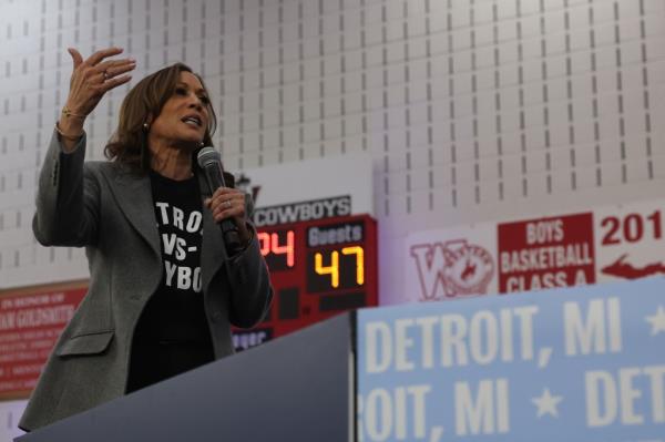 Vice President Kamala Harris speaking into a microphone at a get-out-the-vote rally in Detroit, Michigan, campaigning for the presidential election.