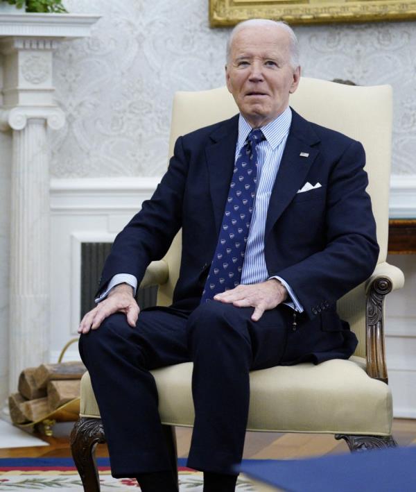 US President Joe Biden in a suit and tie sitting in a chair, meeting with President Isaac Herzog of Israel in the Oval Office at the White House