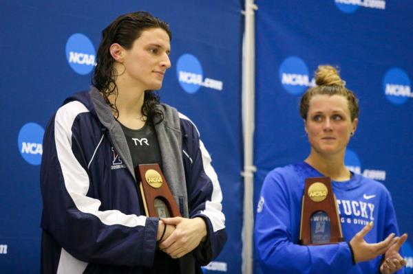 Penn Quakers swimmer Lia Thomas holds a trophy after finishing fifth at the NCAA Swimming & Diving Champio<em></em>nships as Kentucky Wildcats swimmer Riley Gaines looks on.