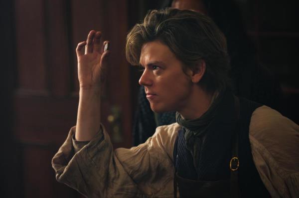 Thomas Brodie-Sangster smirking, face shown in profile. 