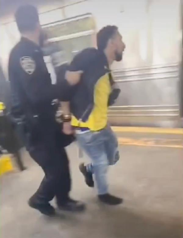 The suspect is seen being taken away by police.