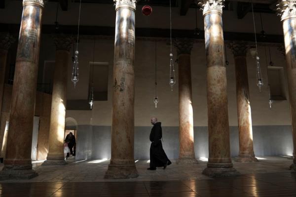 A priest walks through columns in the otherwise empty Church of the Nativity, traditio<em></em>nally believed to be the birthplace of Jesus Christ.