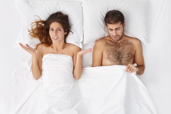Indoor shot of upset female in bed shrugging shoulders in confusion