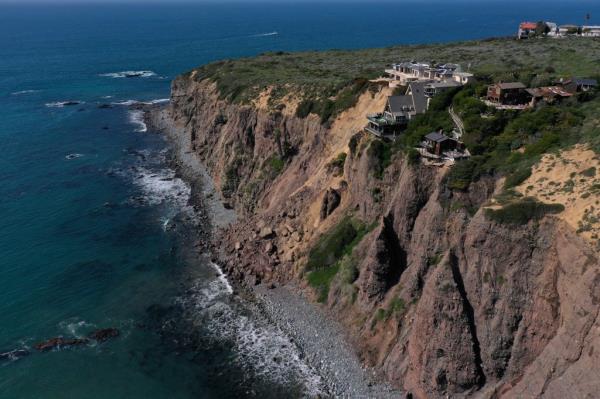 An aerial image shows homes along Scenic Drive standing on the edge of a cliff above the Pacific Ocean after a landslide following heavy rains in Dana Point, California.