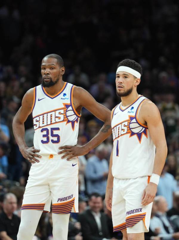 Phoenix Suns players Kevin Durant and Devin Booker standing on the court during a game against the Philadelphia 76ers on March 20, 2024.