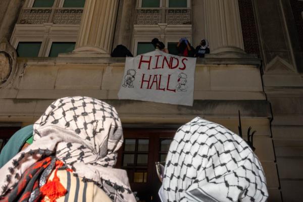 Pro-Palestine demo<em></em>nstrators holding a banner and barricading themselves inside Hamilton Hall at Columbia University during a Gaza Solidarity Encampment protest