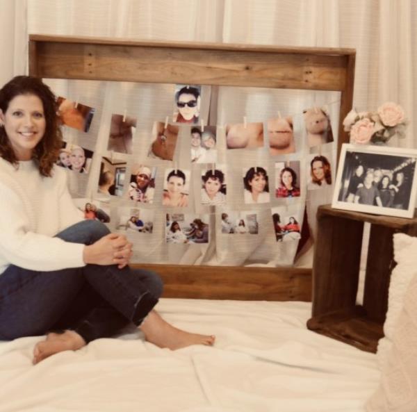 Jennifer sitting in front a large wooden f<em></em>rame, with multiple photos hanging inside it - of breasts after surgery and different hair changes