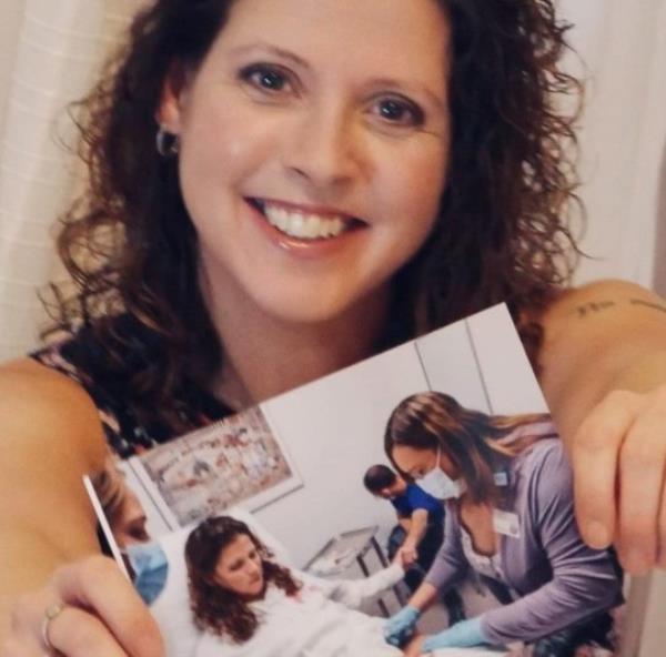 Jennifer holding up a photo of her in a hospital bed, getting tretment from a nurse