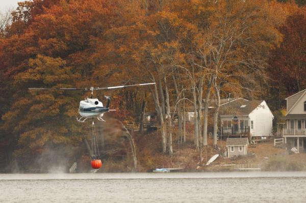 A Bell UN-1H Iroquois helicopter from the Maine Forest Service retrieving water from Silver Lake to combat a wildfire on Lamentation Mountain in Berlin, Connecticut.