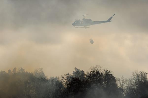 A Bell UN-1H Iroquois helicopter from the Maine Forest Service dropping water o<em></em>nto a wildfire on Lamentation Mountain in Berlin, Connecticut, USA