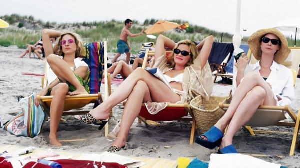 Kim Cattrall, Sarah Jessica Parker, and Cynthia Nixon sitting on beach chairs in a scene from Sex and the City (1998)