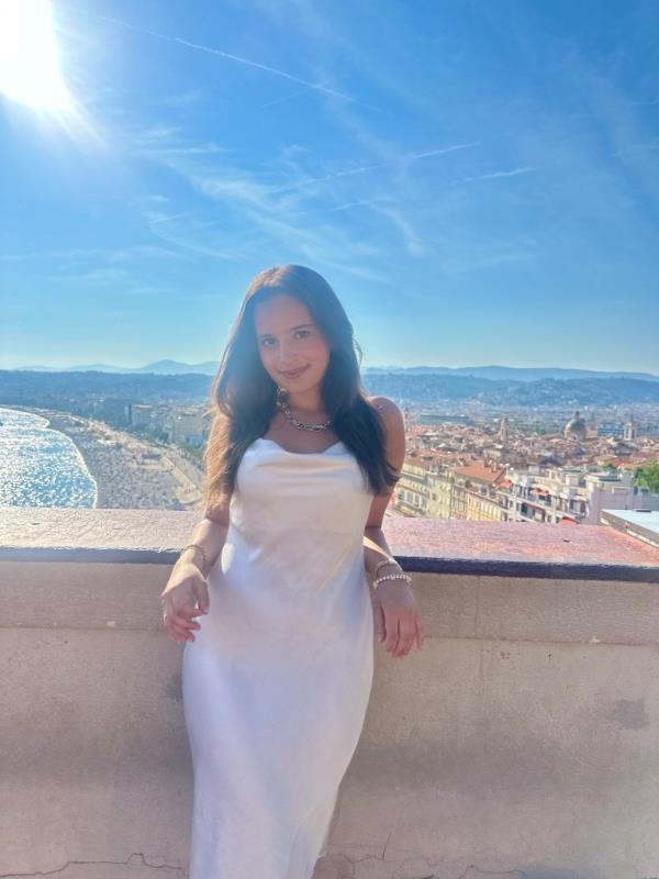 Madison Hecht poses in a white dress while the sun shines.