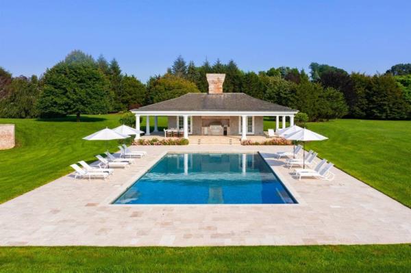 A pool with chairs and umbrellas in front of a house in Water Mill, NY