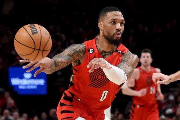 Portland Trail Blazers guard Damian Lillard, left, passes the ball against the Washington Wizards during the first half of an NBA basketball game in Portland, Ore., Tuesday, Feb. 14, 2023