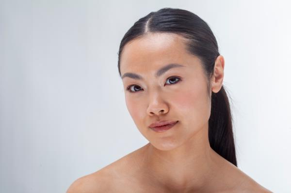 A young woman with her hair pulled back in a po<em></em>nytail with a middle part.