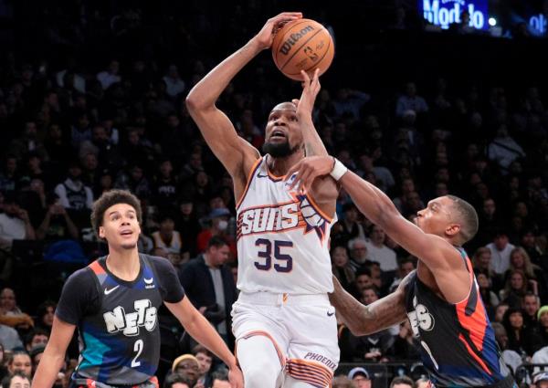 Kevin Durant drives to the basket between Cam Johnson (left) and Lo<em></em>nnie Walker IV during the Nets' loss to the Suns.