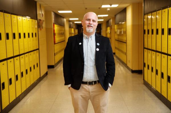 Teacher Joseph Nappi at Mo<em></em>nmouth Regio<em></em>nal High School in New Jersey, in the halls, surrounded by yellow lockers. 
