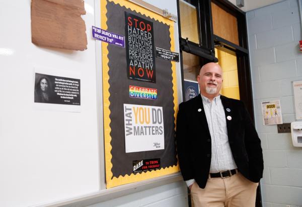 Teacher Joseph Nappi in classroom, leaning against a wall. 